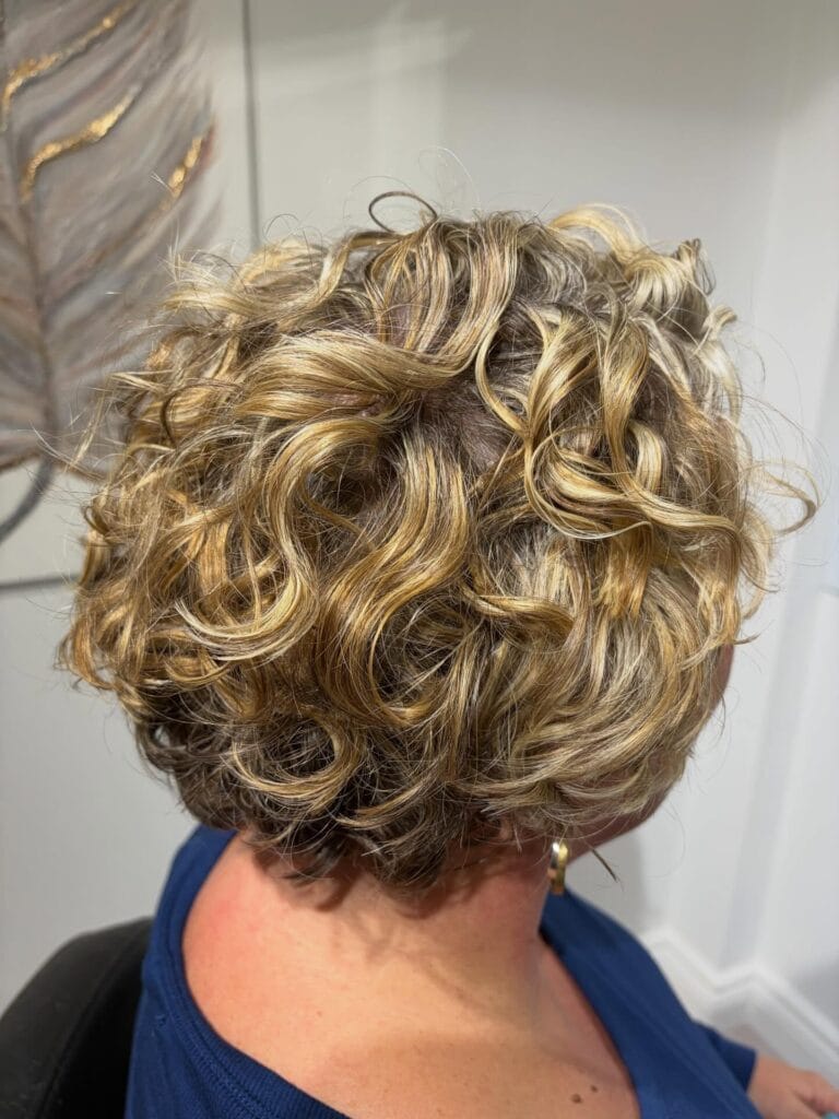 Short curly bob with blonde highlights and bouncy defined curls creating a voluminous shape.