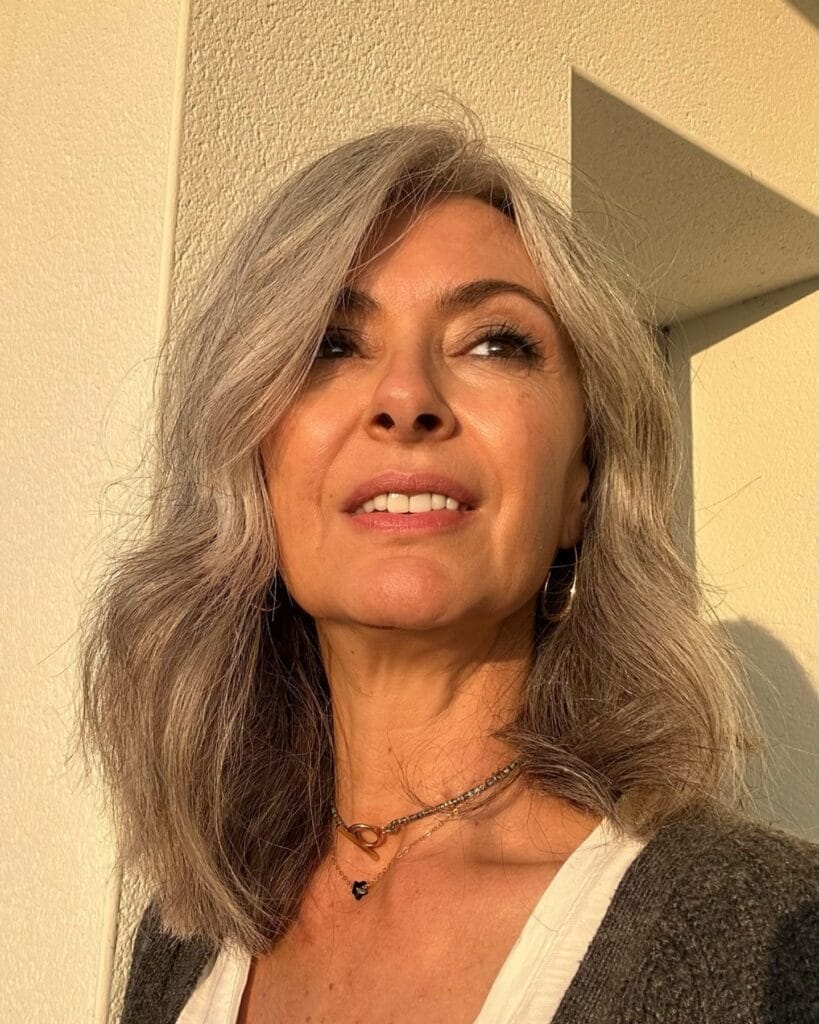 Medium length gray wavy hairstyle with soft layers and natural movement.