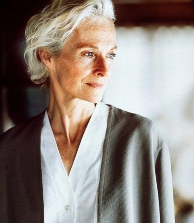 Short silver wavy hairstyle with soft swept back layers and natural movement.