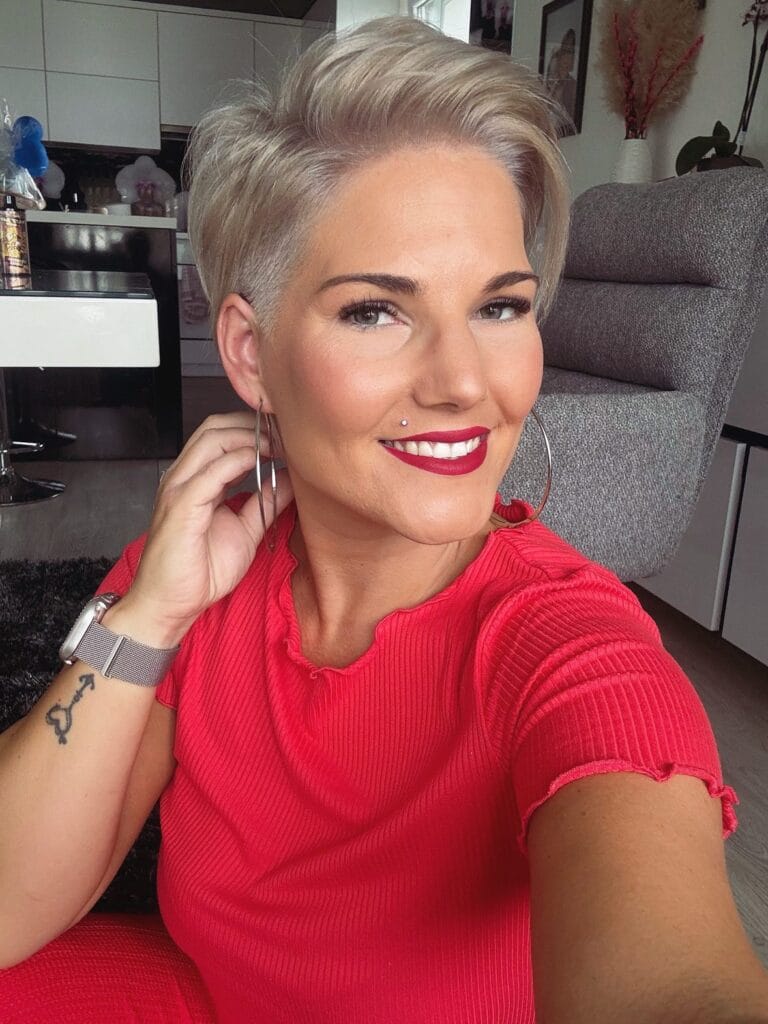 Short silver wavy pixie haircut with tapered sides and soft volume on top.