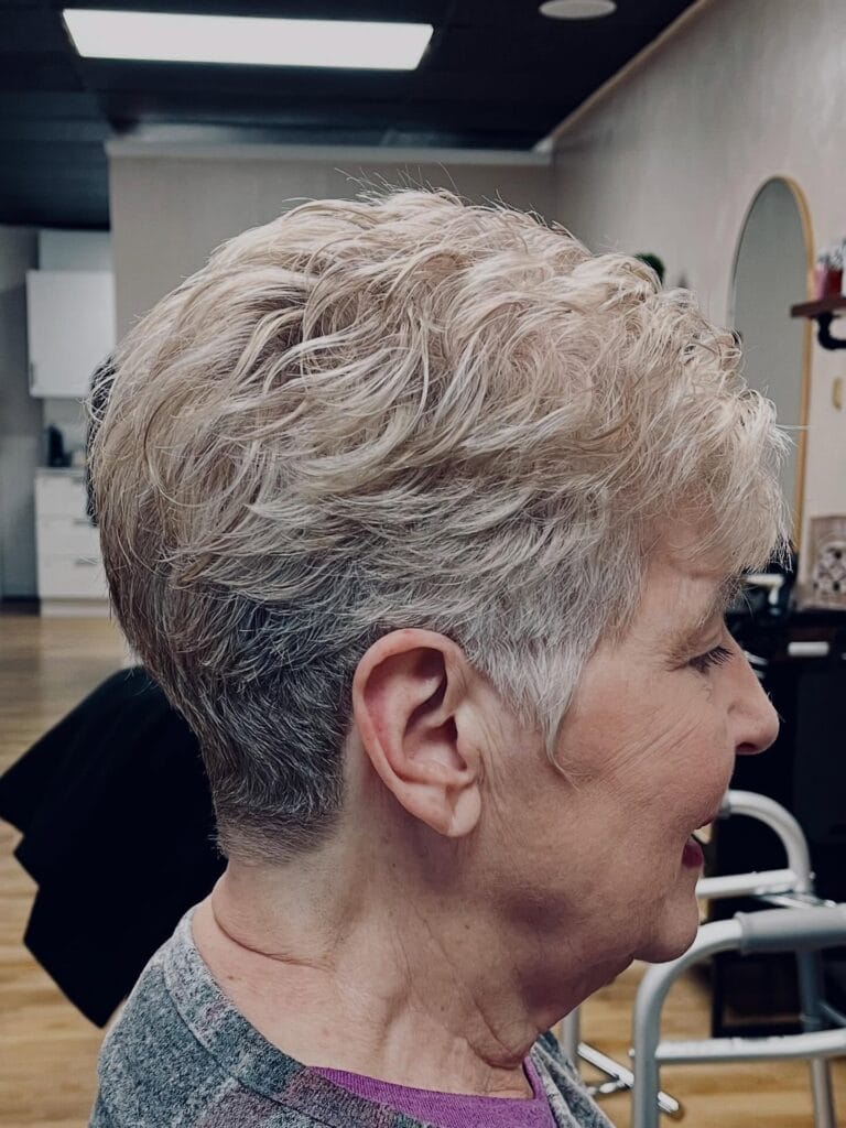 Short silver textured pixie with soft wavy layers and volume on top.