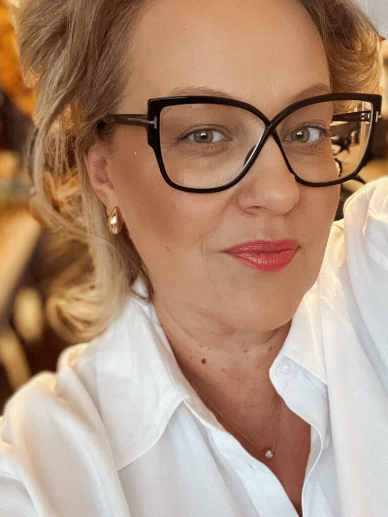 Short layered blonde bob hairstyle worn with black glasses.