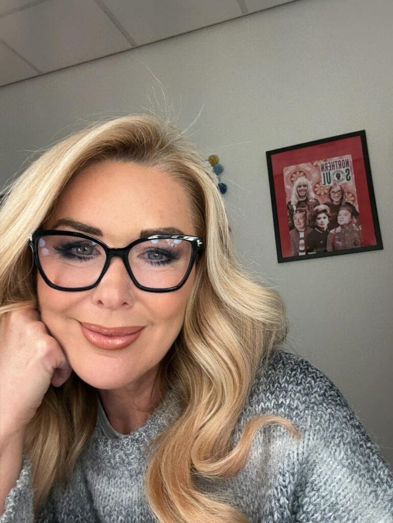 Long blonde hair with loose waves worn with black cat eye glasses.