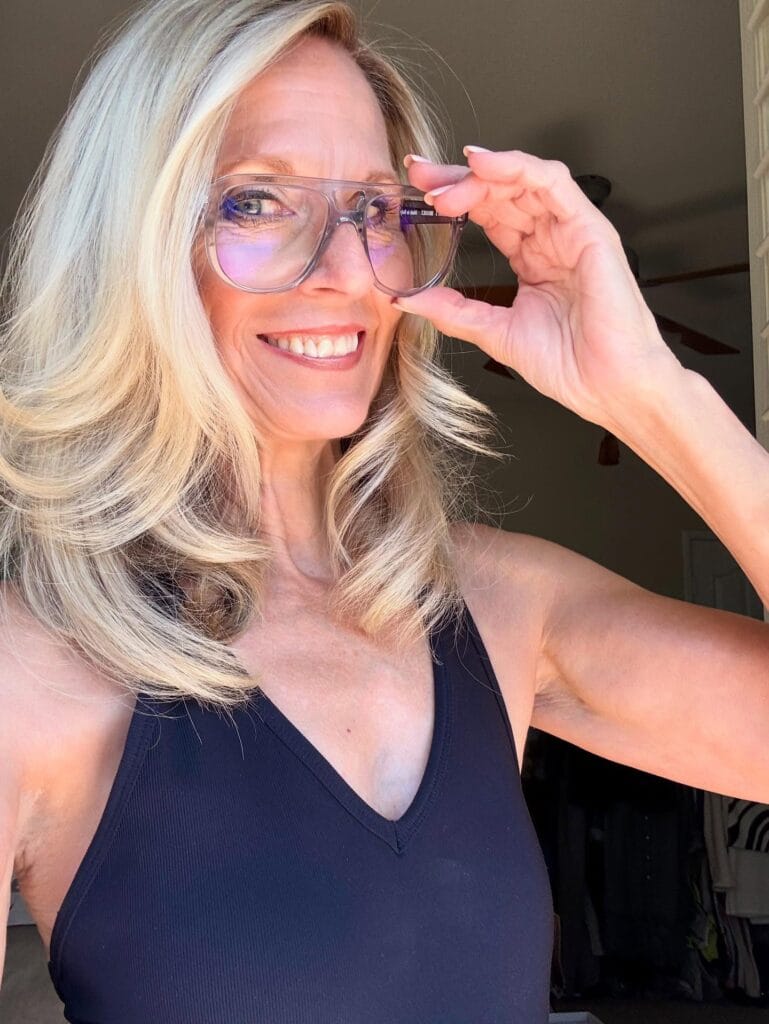 Shoulder length platinum blonde hair with loose waves worn with clear glasses.