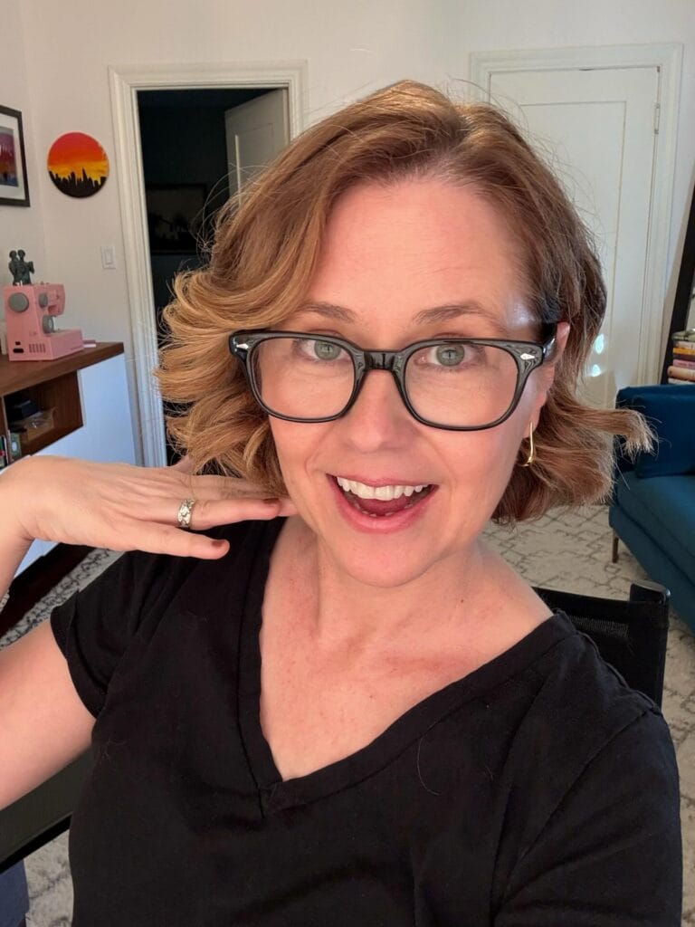 Short wavy bob hairstyle with soft layers worn with rectangular glasses.