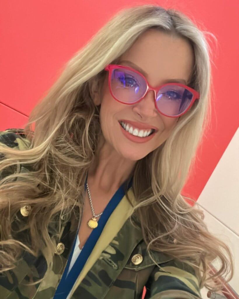 Long blonde wavy hairstyle worn with colorful glasses.