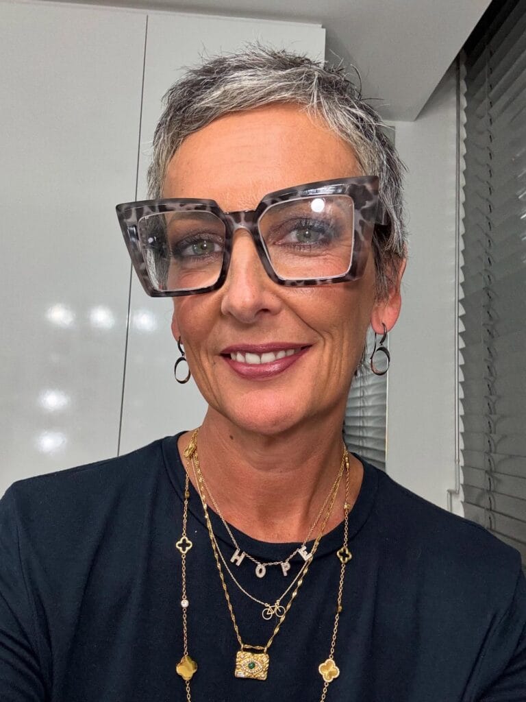 Short silver textured crop hairstyle worn with oversized square glasses.