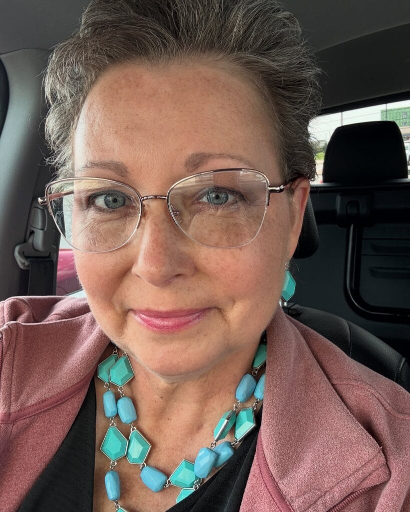 Short salt and pepper tapered haircut worn with thin metal glasses.