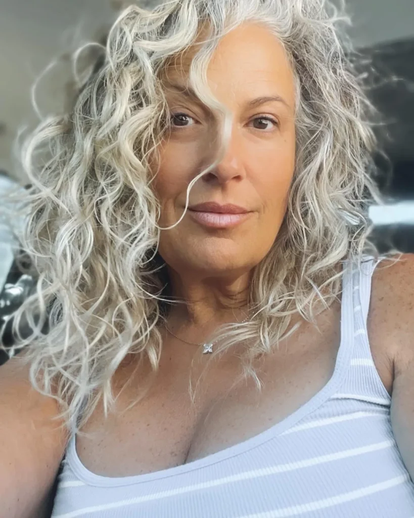 Shoulder length silver curly hairstyle with soft volume and natural texture.