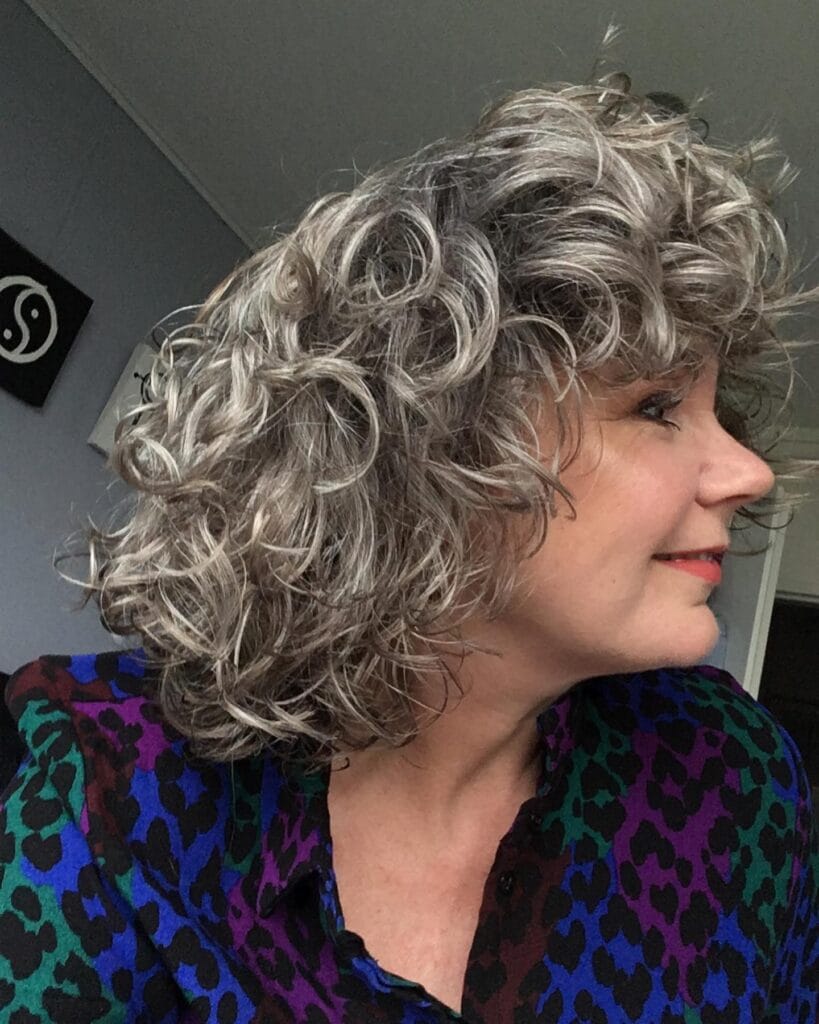 Short silver curly bob with tight curls and voluminous shape.