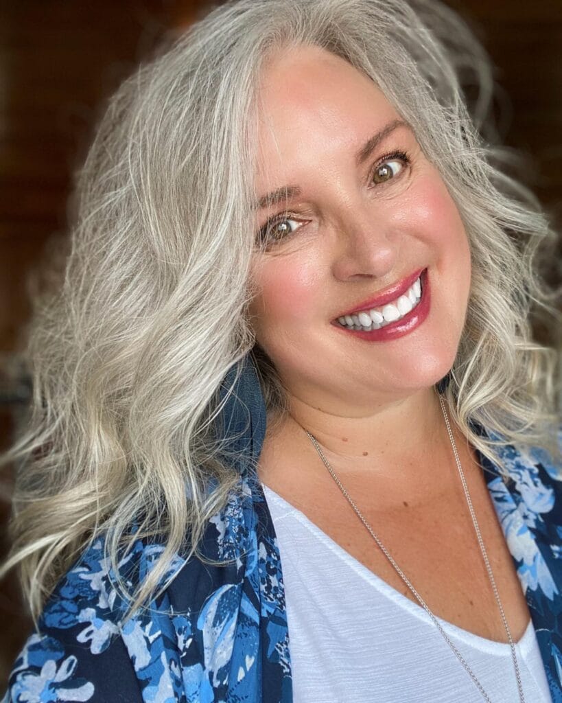 Long silver curly hairstyle styled into voluminous soft waves.