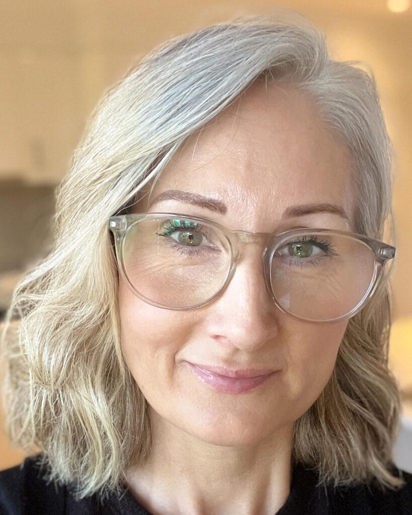 Shoulder length curly bob with soft waves and silver blonde tones.