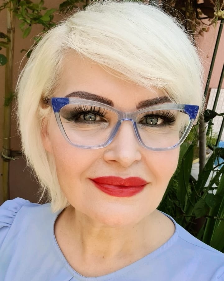 A woman with a bright platinum blonde bob styled with a deep side part and long sweeping bangs.