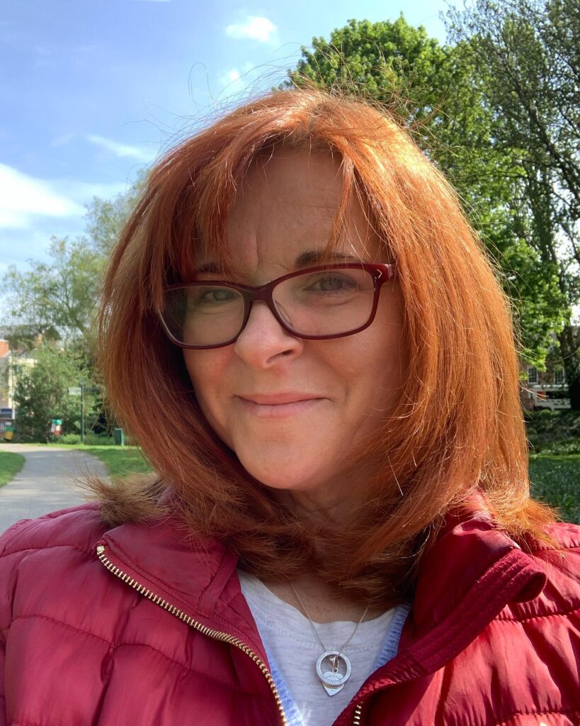 A woman with vibrant copper red shoulder-length hair styled with soft inward-curving layers and light bangs.