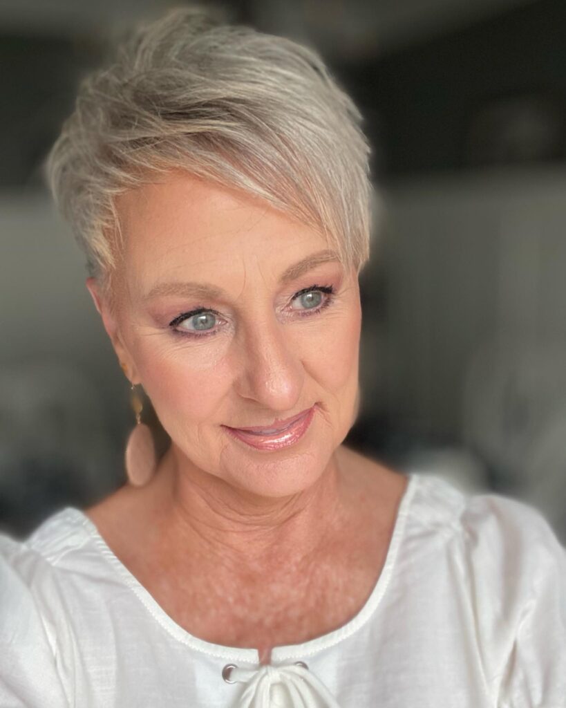 A woman over 50 with a short ash-blonde spiky pixie cut featuring tapered sides and textured piecey layers on top.