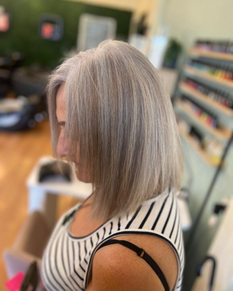 A woman in profile with a straight-angled bob in a cool mushroom blonde shade.