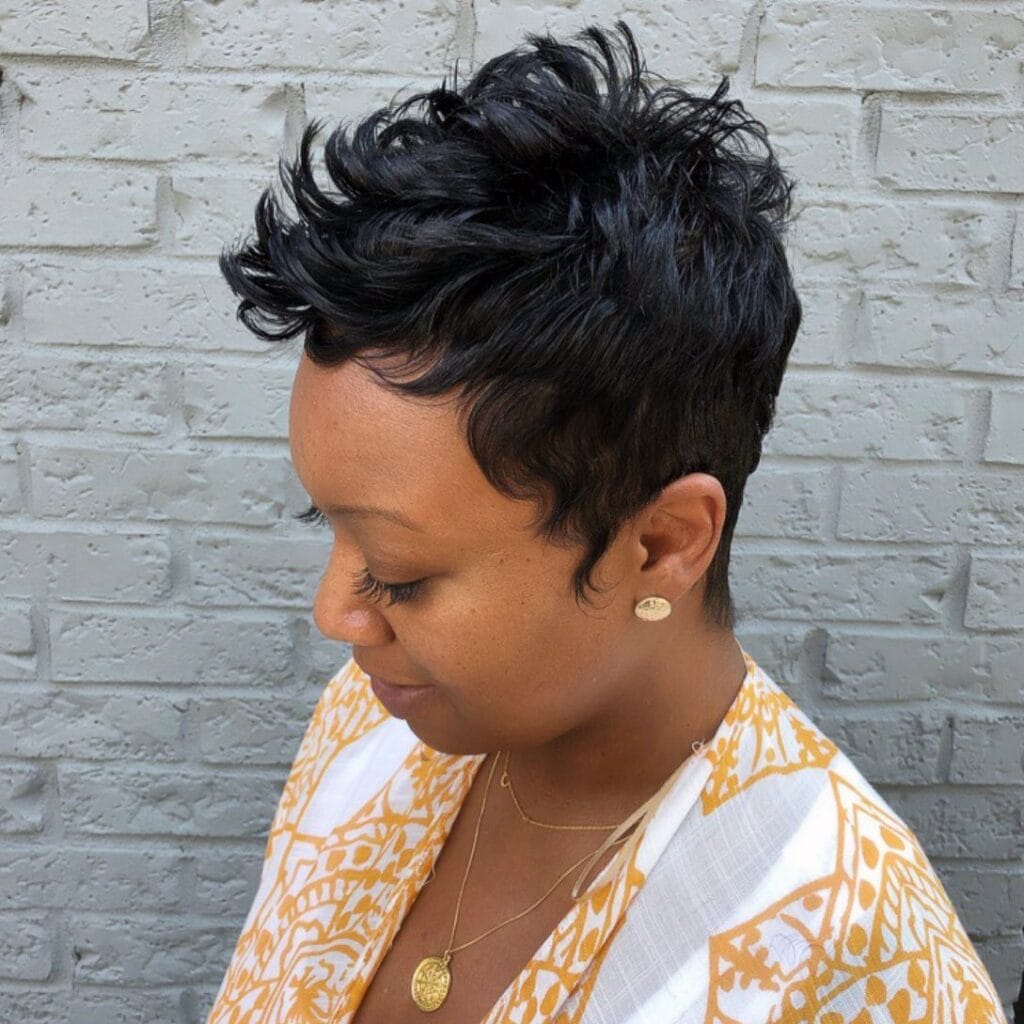 Jet black textured pixie haircut with short cropped sides and layered top.