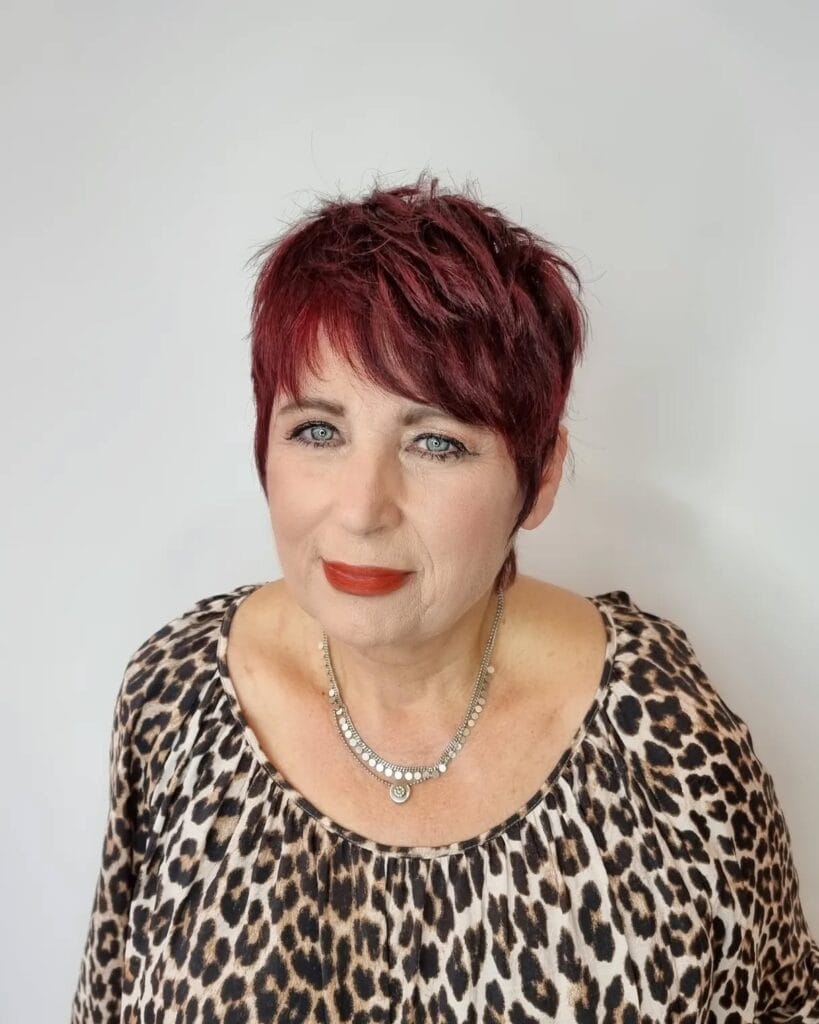 Ruby red choppy pixie haircut with textured top and short sides.