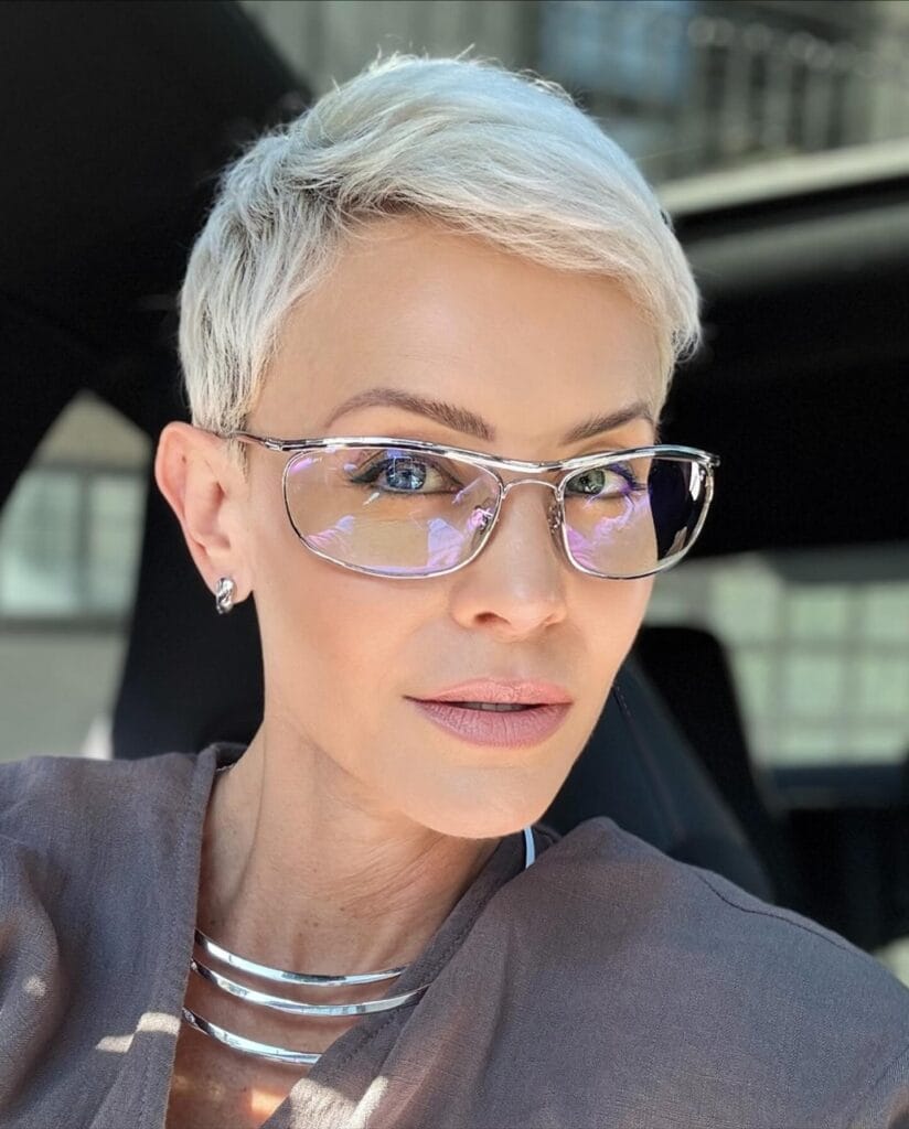 Icy blonde pixie haircut with short sides and softly textured top layers.