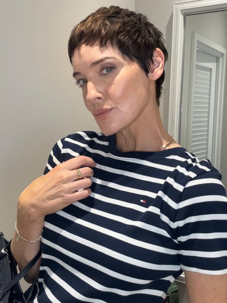 Ultra short brunette micro pixie haircut with choppy texture and cropped sides.