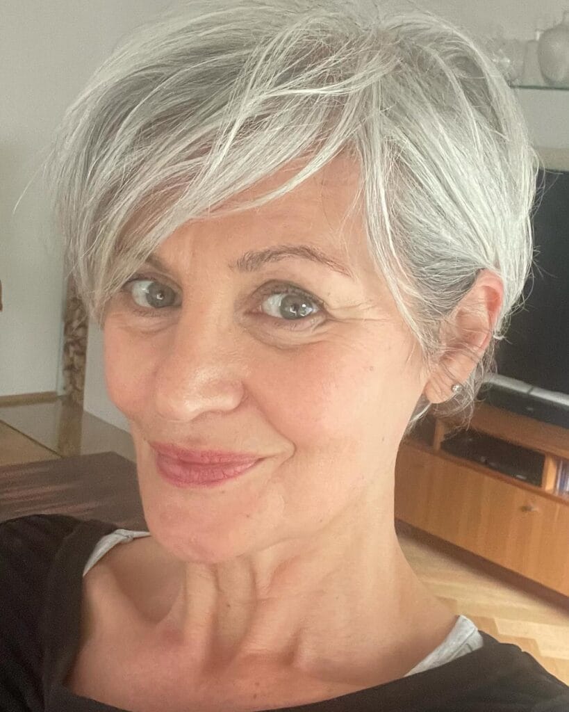 Silver pixie haircut with side swept fringe and short layered sides.