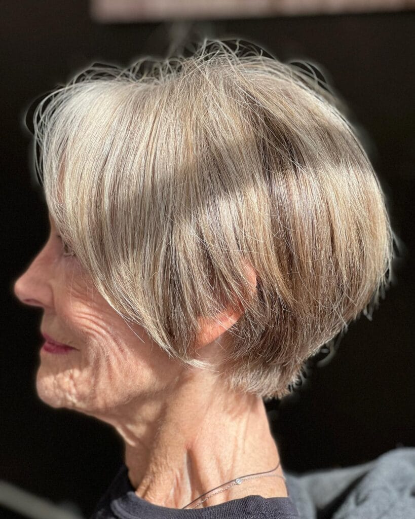 Platinum blonde layered pixie bob haircut with rounded shape and short back.