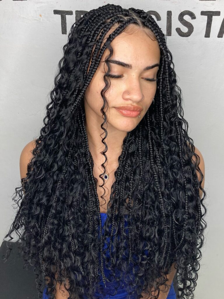 Long jet black goddess braids with curly textured strands and a center part.