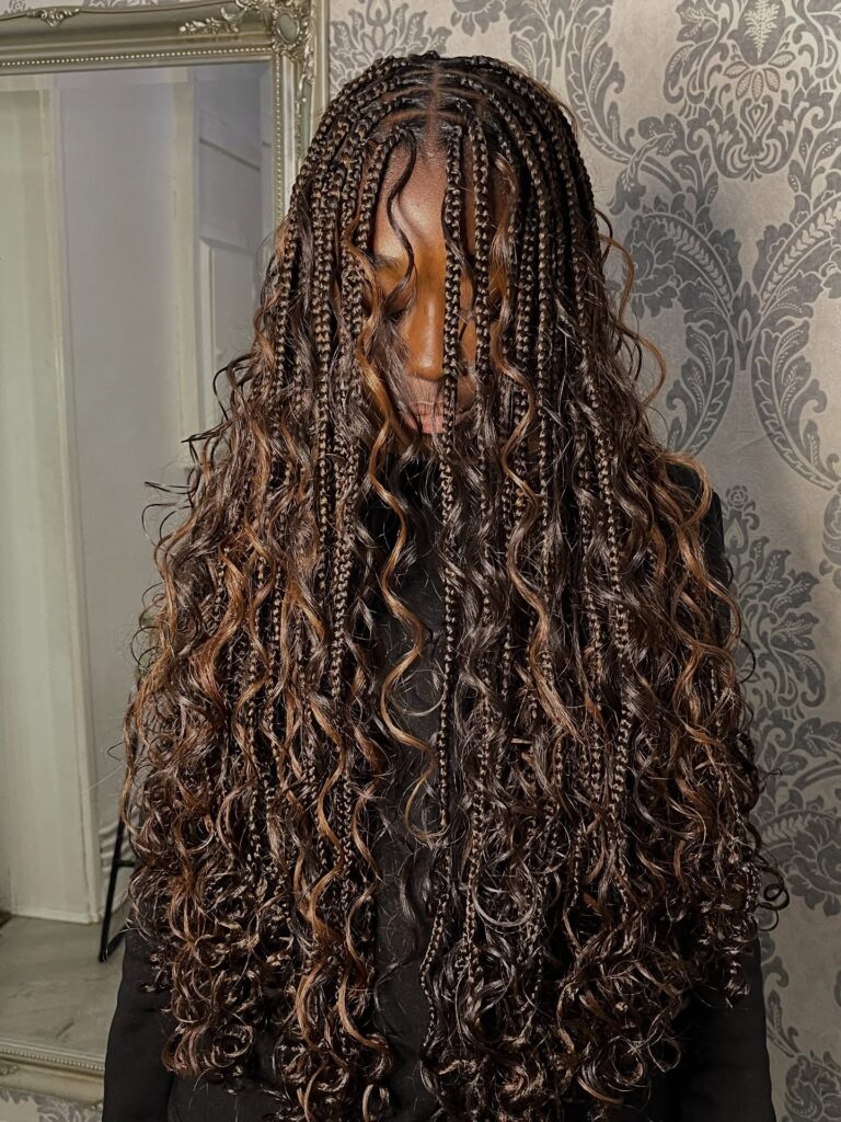 Long dark brown goddess braids with loose curly strands and soft caramel highlights.