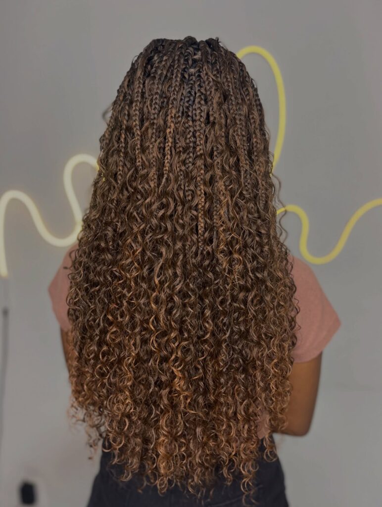 Long cinnamon brown goddess braids with tight curls and fine braided sections.