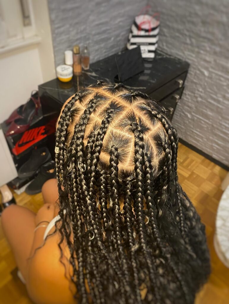 Glossy black goddess braids with loose curly strands and clean square braid sections.