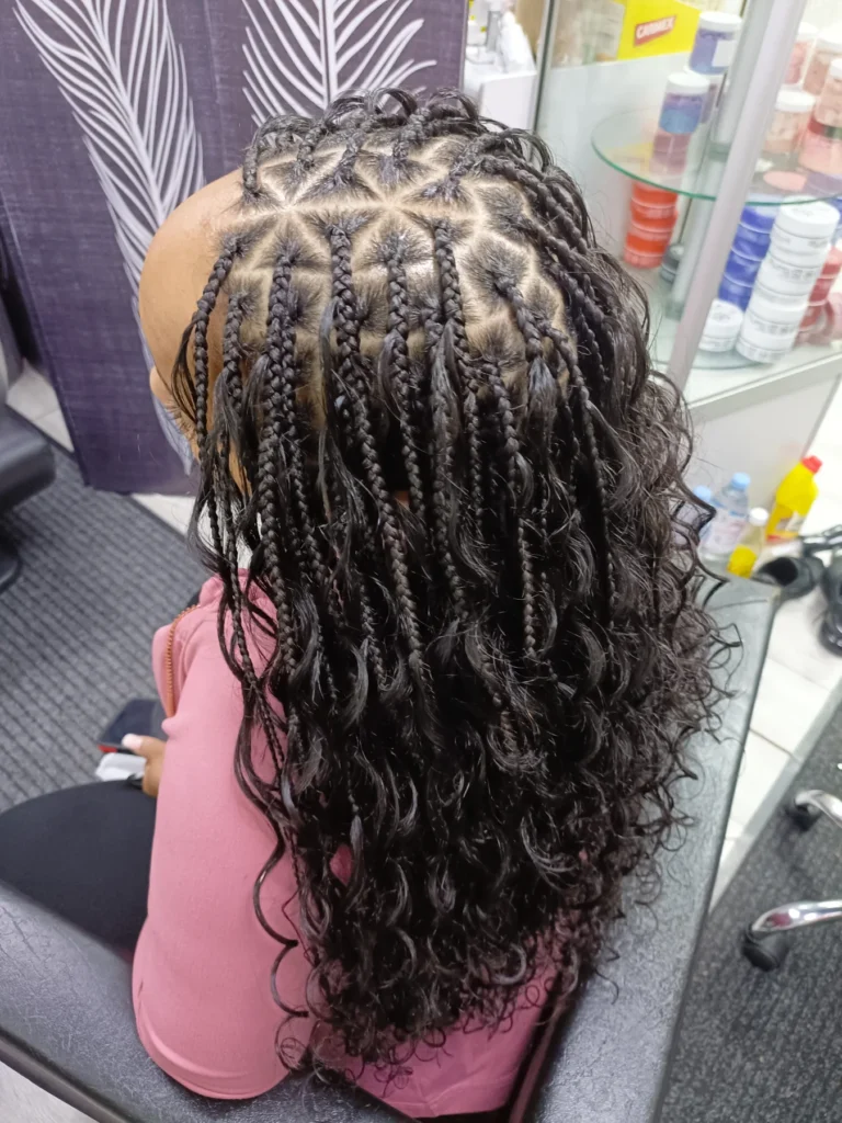 Black goddess braids with star shaped parting and loose curly strands.