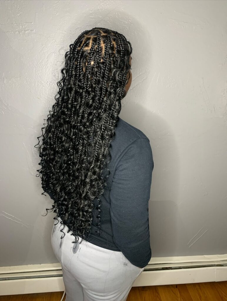 Midnight black goddess braids with tight curly ends and layered texture throughout.