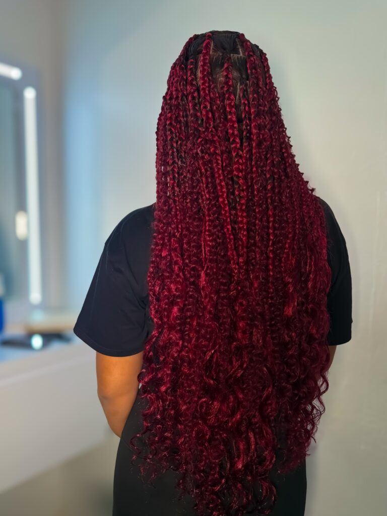 Long deep red goddess braids with tight curly ends and a voluminous finish.