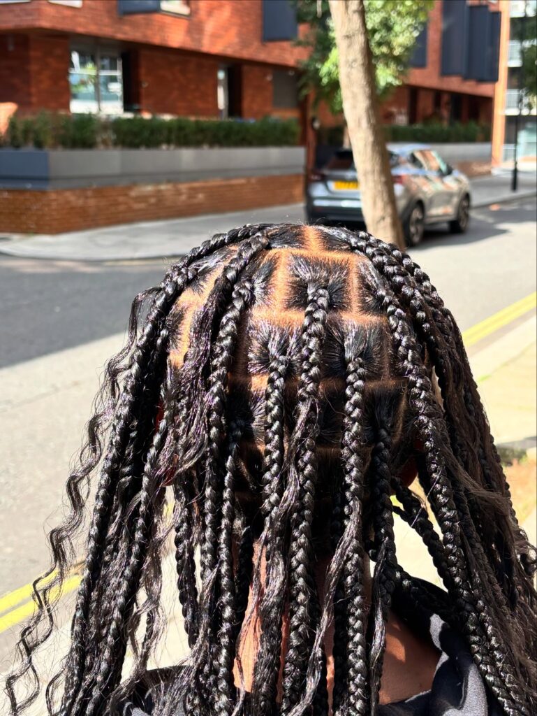 Long black knotless goddess braids with wavy strands and neat square parts.