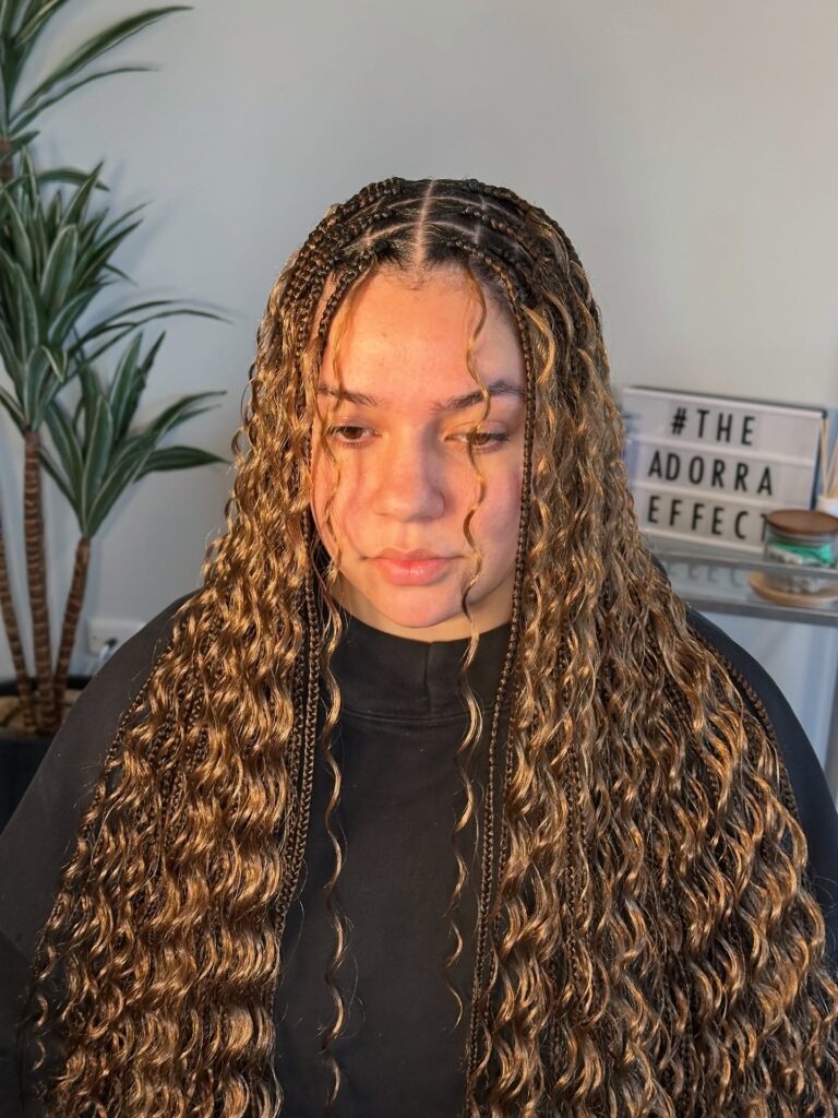 Long honey blonde goddess braids with soft crimped waves and curly face framing strands.