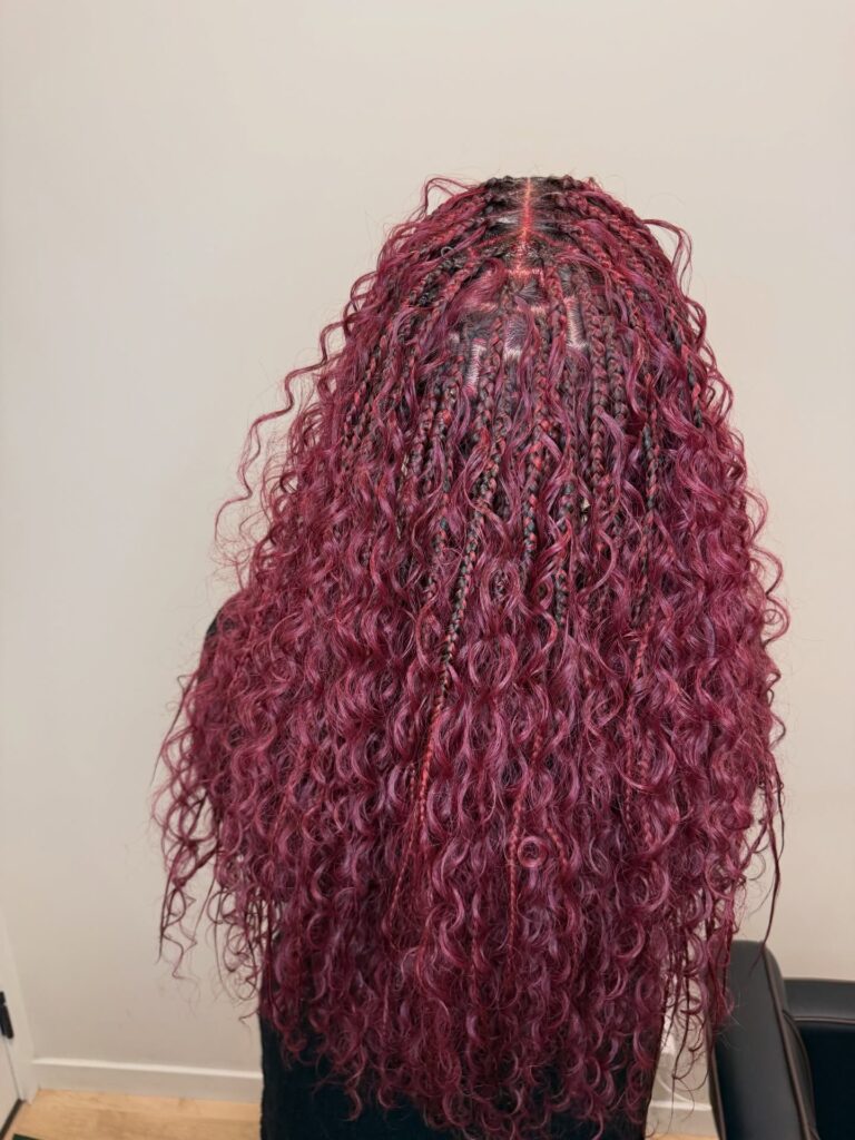Long berry wine goddess braids with curly textured strands and deep burgundy coloring.