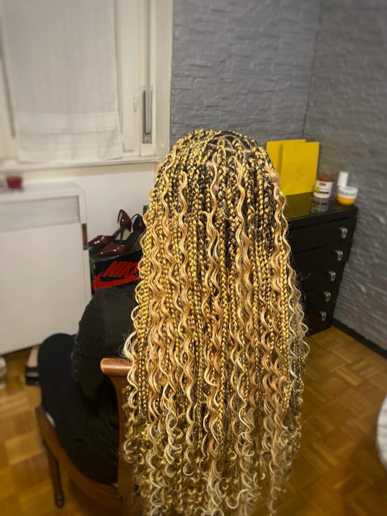Golden blonde goddess braids with darker roots and loose wavy highlighted strands.