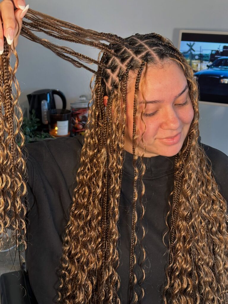 Long ash blonde goddess braids with dark roots and soft wavy curls throughout.