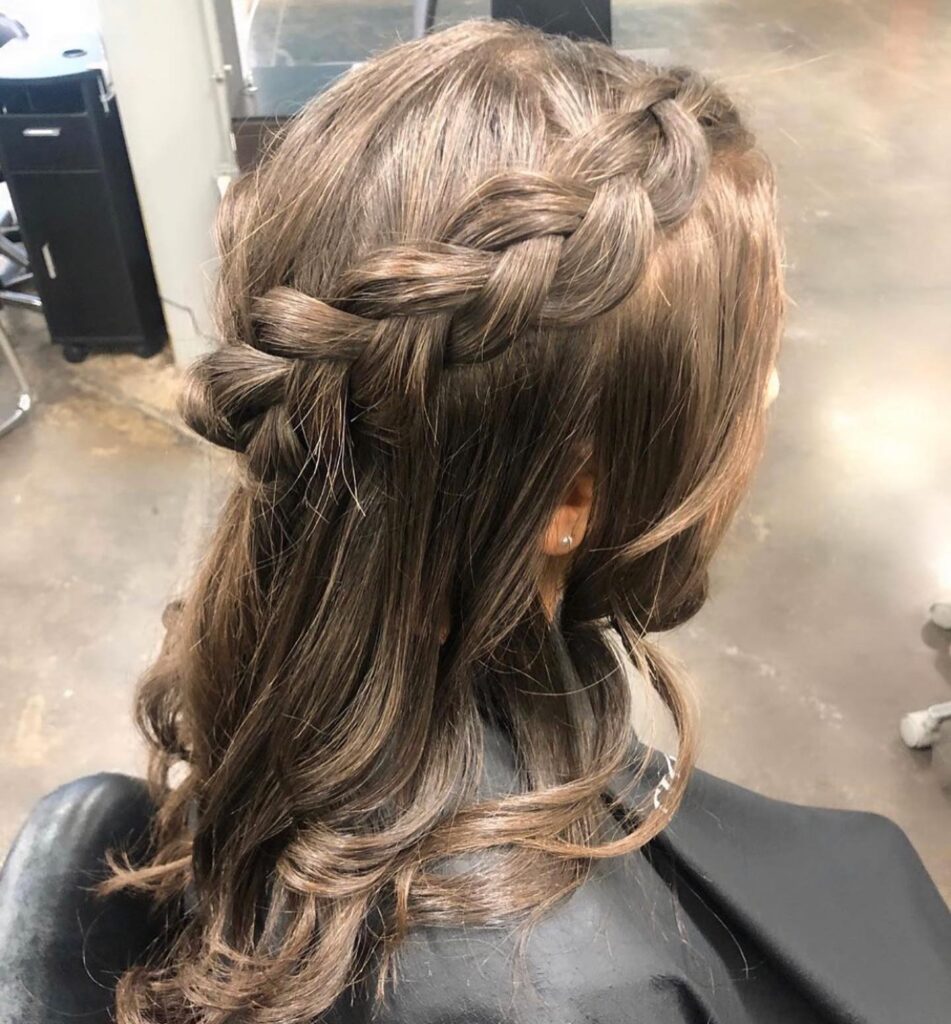 A brunette hairstyle with loose curls and a thick Dutch braid in a half up style.