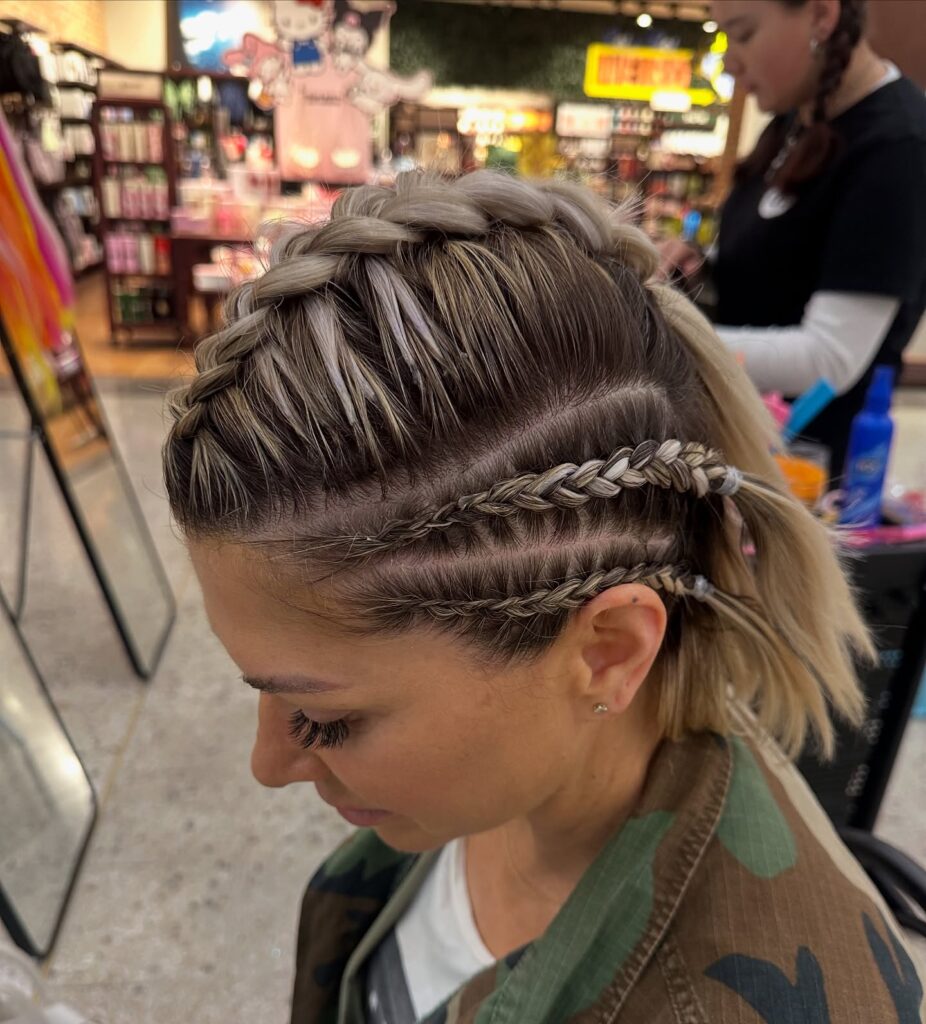 A short highlighted bob with a chunky Dutch braid and small braided undercut details.