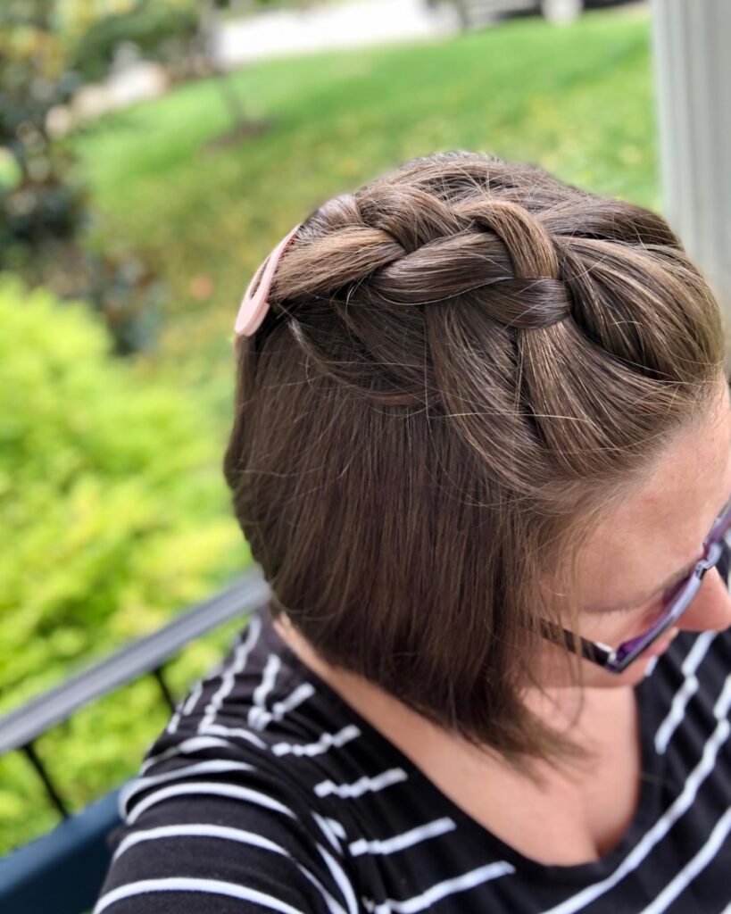 A short brown bob hairstyle with a thick Dutch braid wrapped across the crown.