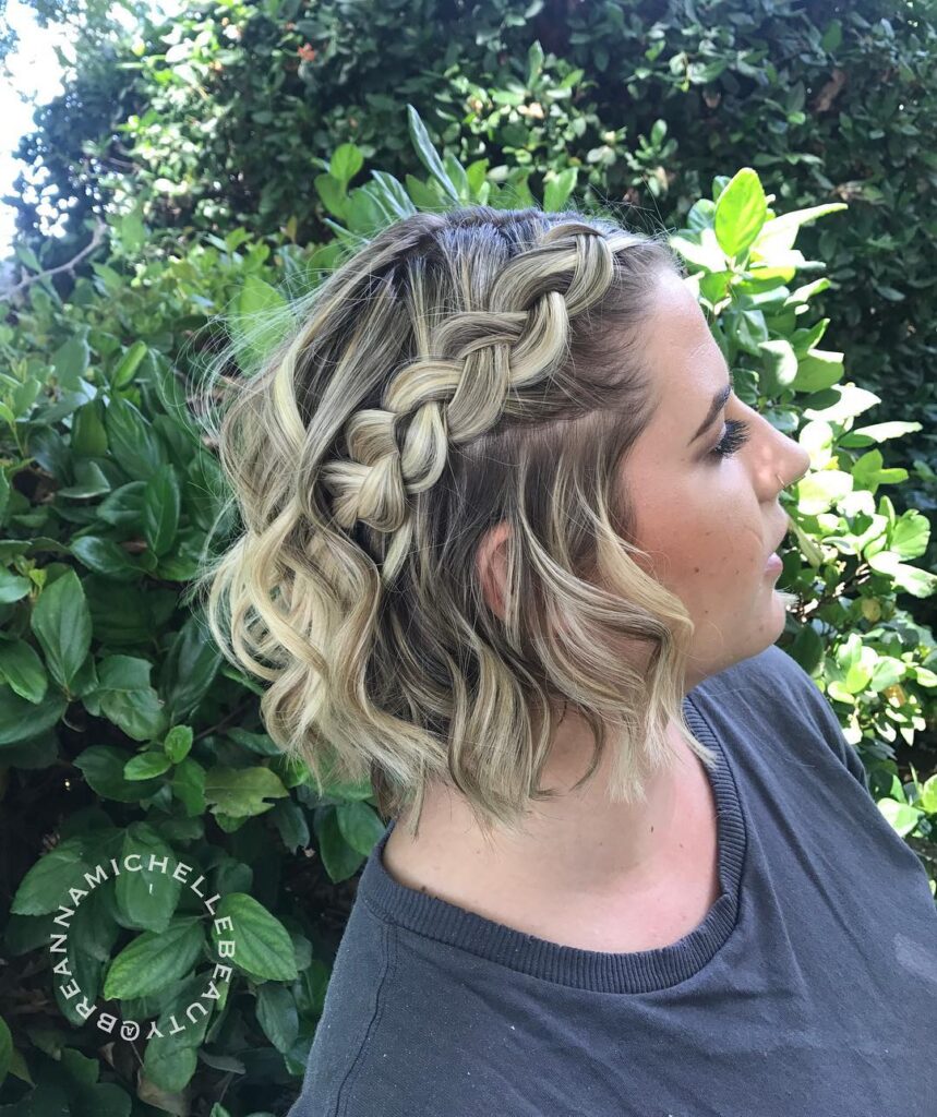 A short wavy blonde bob with a thick side Dutch braid and beachy texture.