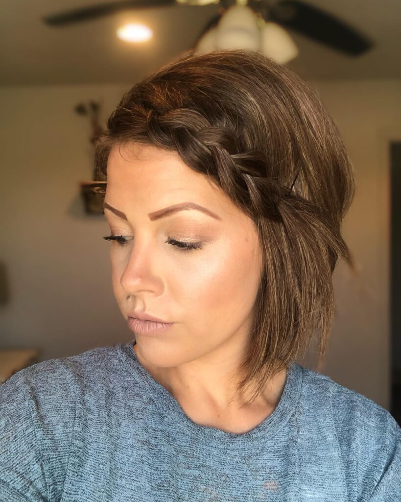 A short brown bob hairstyle with a loose side Dutch braid and soft straight layers.