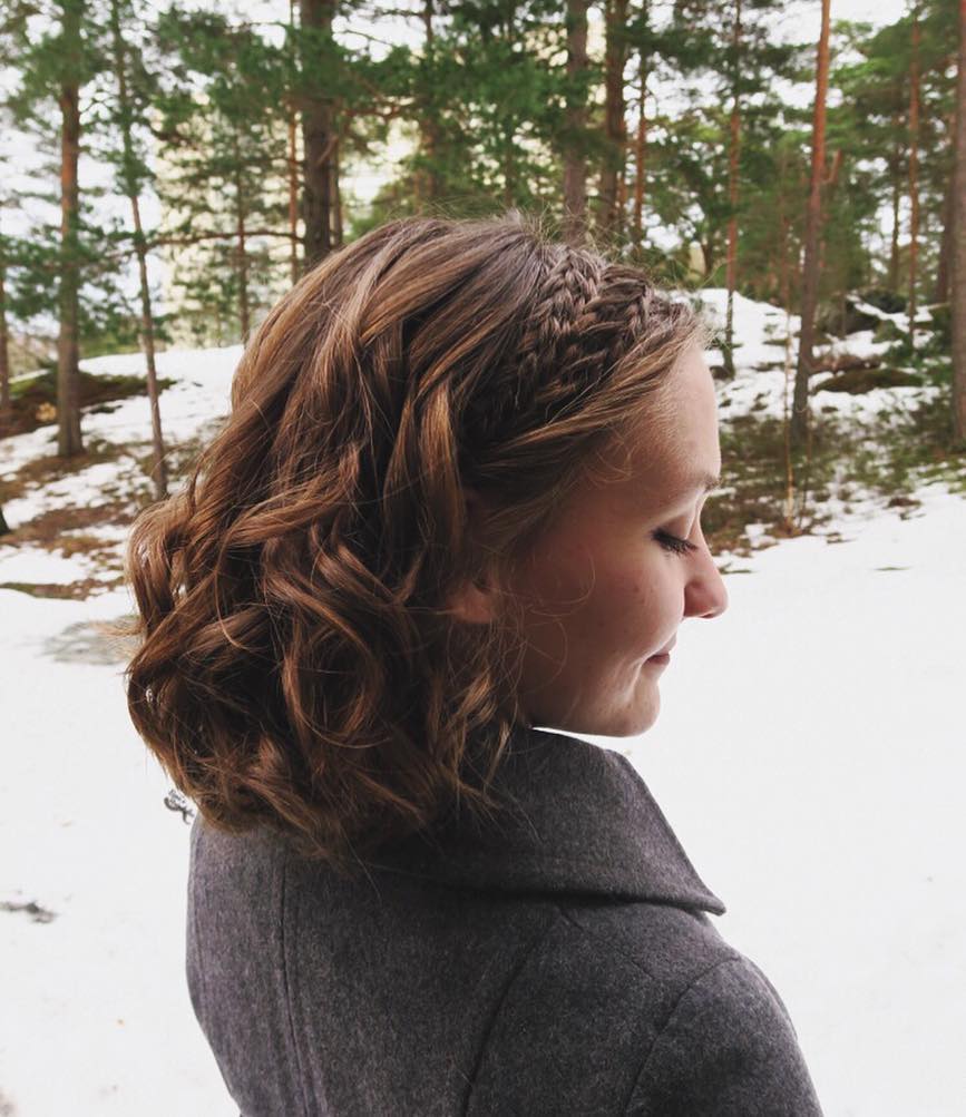 A wavy short lob with a thin Dutch braid along the side and soft curled texture.