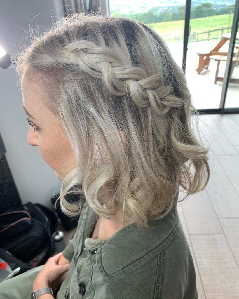 A platinum blonde wavy lob with a thick Dutch braid along one side.