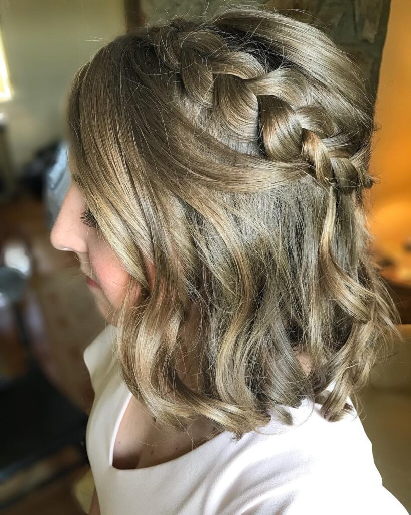 A wavy blonde lob hairstyle with a thick Dutch braid along one side.