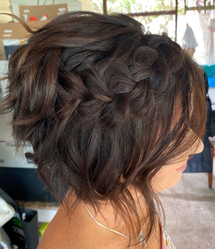A messy brunette bob hairstyle with a thick side Dutch braid and loose textured waves.