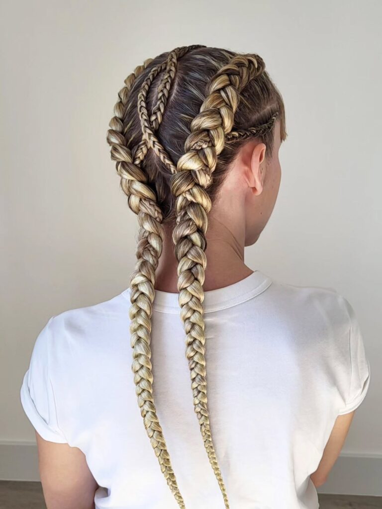 Intricate Dutch braid hairstyle with thick blonde braids and smaller accent braids on long hair.