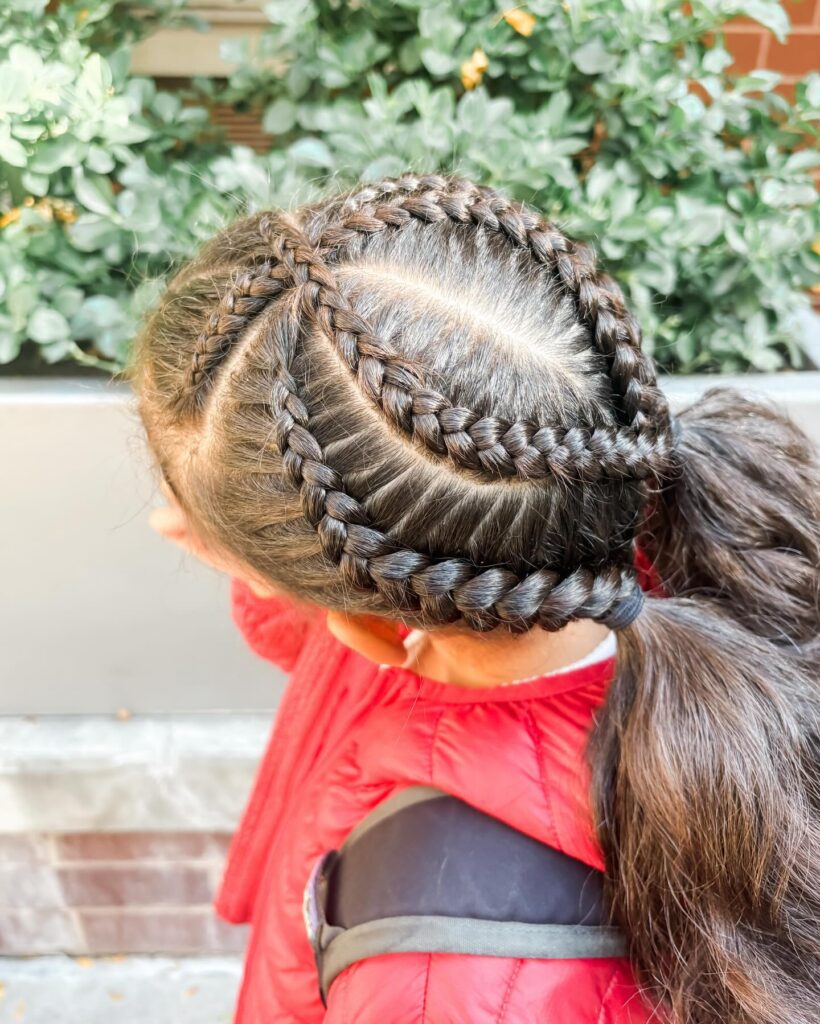 Curved Dutch braids wrapped around the head and gathered into a low ponytail.
