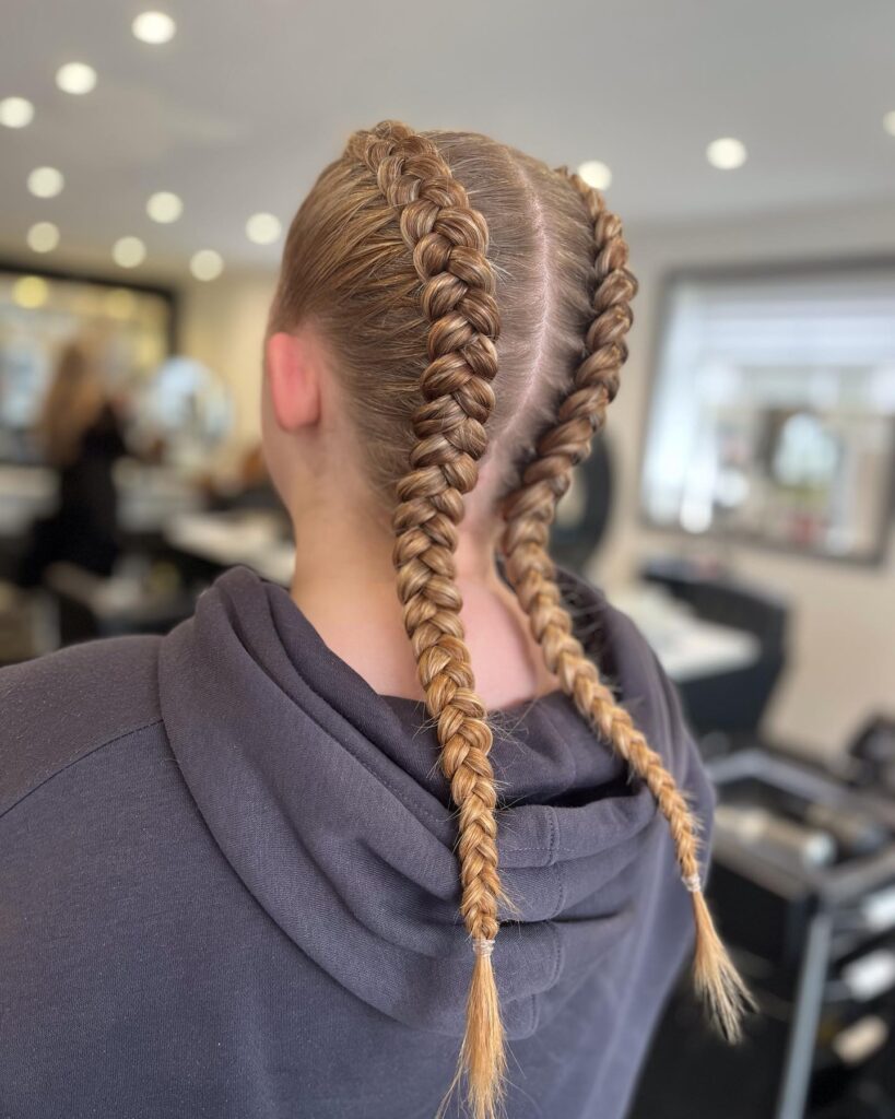 Long sleek golden blonde Dutch braids with a smooth polished finish.
